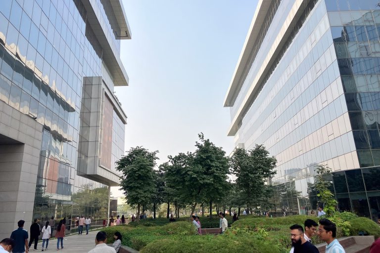 Exterior campus grounds showing a landscaped plaze between two impressive multi story buildings shining in the Indian sunlight