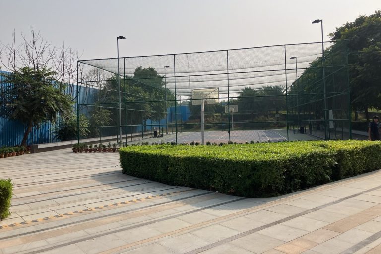An external multi-purpose sports area with secure perimeter fences, netting and lights for night-time play