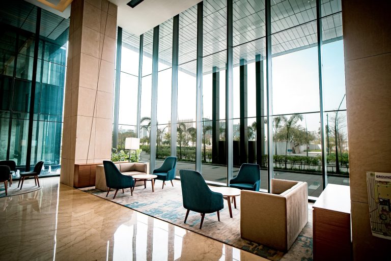 A spacious and comfortable lobby with seating and casual tables flooded with natural light from floor to ceiling windows