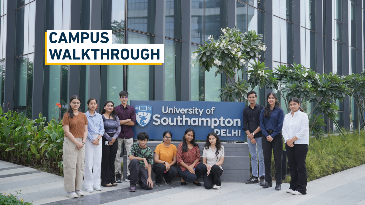 Smiling students look towards camera around a monolith sign showing the University of Southampton Delhi logo