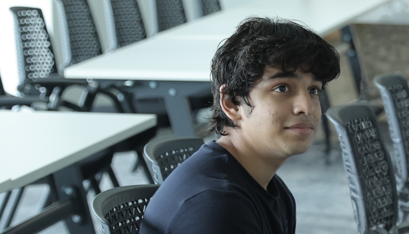 A Creative Computing BSc (Hons) degree looks to the right of camera as they sit in a study space