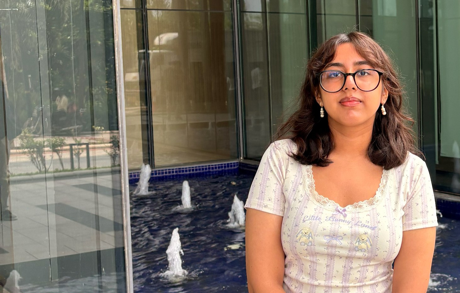 A Computer Science BSc (Hons) degree student stands outside in the university campus and looks toward camera