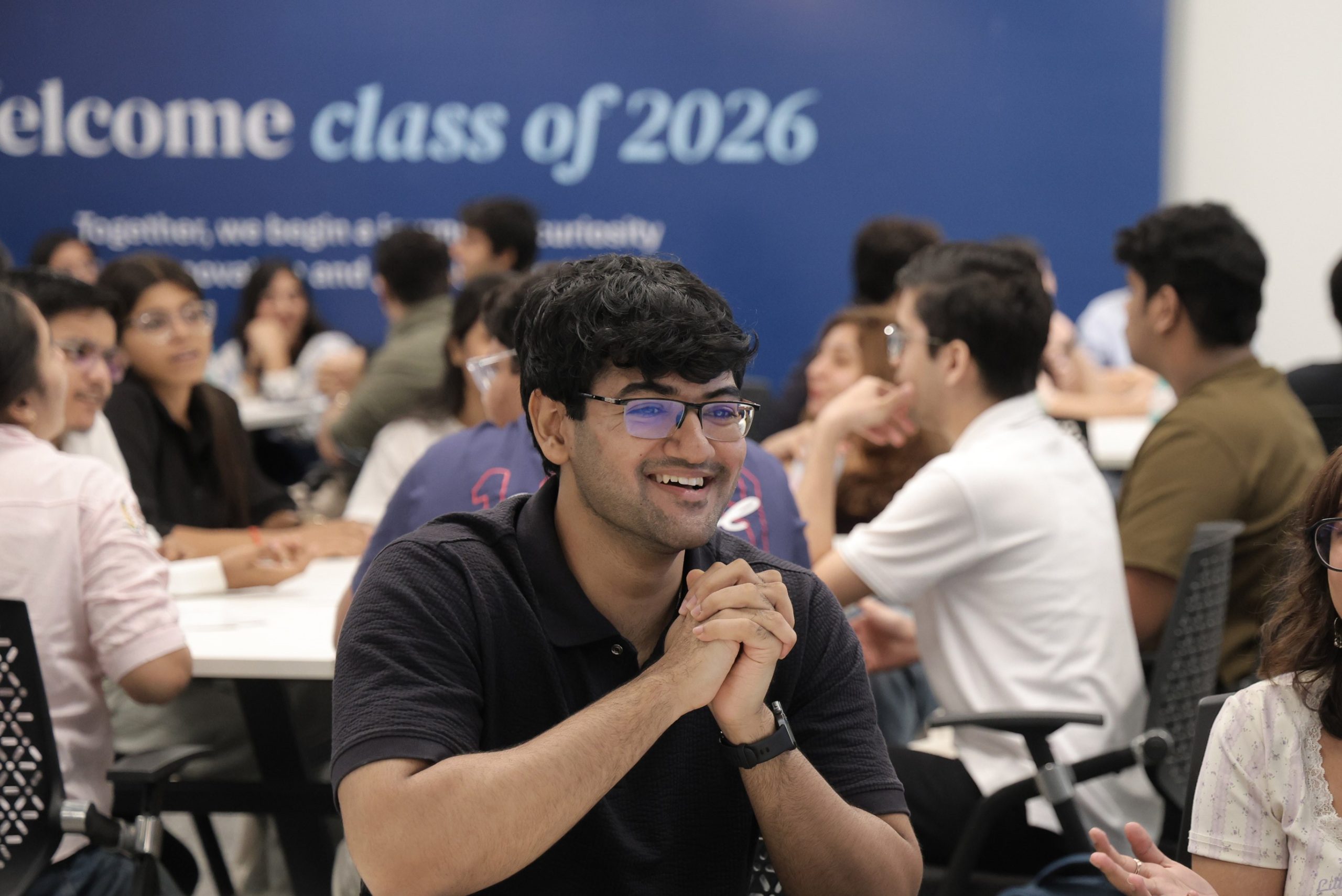 A Data Science MSc degree student smiles and looks to the right of camera as they talk to fellow students