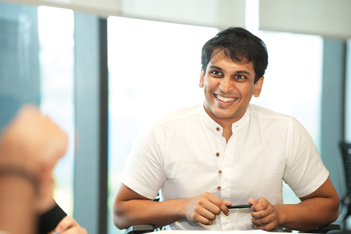 A Finance MSc degree student smiles and looks to the left of camera as they talk to another student